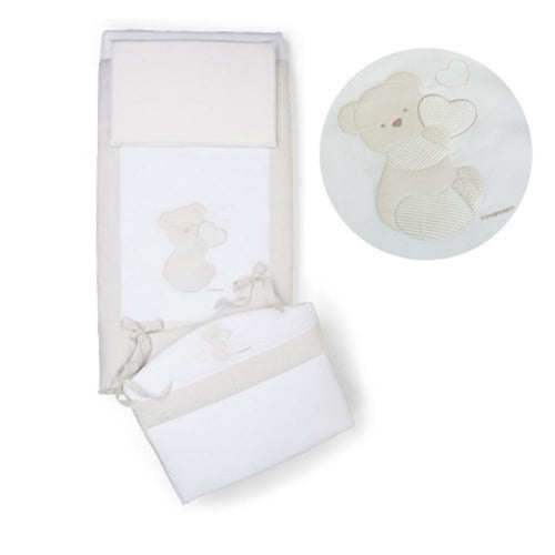 Cream-colored baby crib bedding set featuring embroidered teddy bear holding a heart. 
