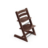 Dark brown wooden high chair with adjustable seat and footrest stands against a white background. 

