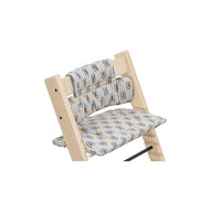 Wooden high chair featuring a removable cushion set with a playful rainbow and star pattern on light gray fabric. 
