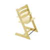 Pale yellow wooden high chair with adjustable seat and footrest on white background. 
